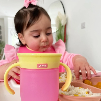 Peuter die drinkt uit een beker met een ministicker