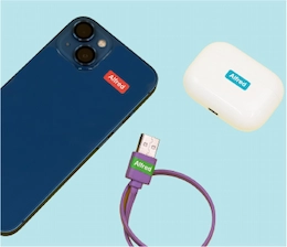 Telefoon, oordopjeshoesje en oplaadkabel met een ministicker